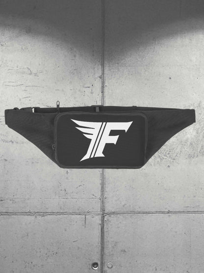 Frontal view of a black zippered waist bag, emphasizing the white 'F' logo. Shot against a gray, industrial background texture.